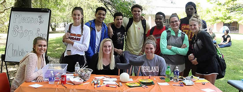 A diverse group of Highland students sitting at a table with markers and papers.
