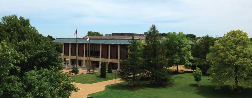 Highland Community College campus features buildings surrounded by lush grass, trees, and walking paths.