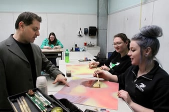 students and faculty discussing an watercolor painting 