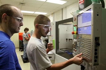 Picture of student and teacher working on computerized equipment 