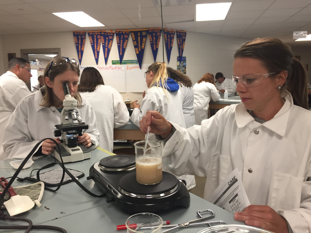 highland staff and students in lab coats testing food samples in lab classroom setting