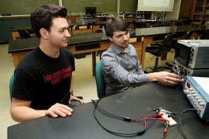 Two male students at a lab table in the highland physics lap using equipment
