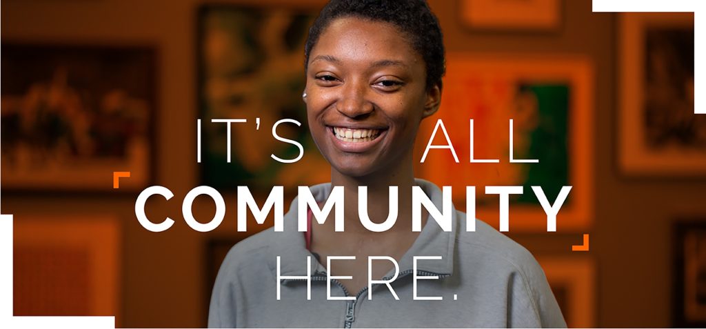 It's All Community Here with a female student standing in the cafeteria