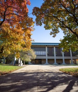 Highland Community College's campus is shown looking through the trees toward the Marvin Burt Liberal Arts Center