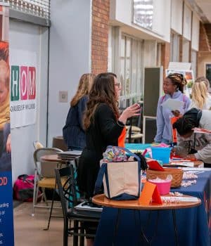 Students stand at a Highland table talking to an Early Childhood Education instructor