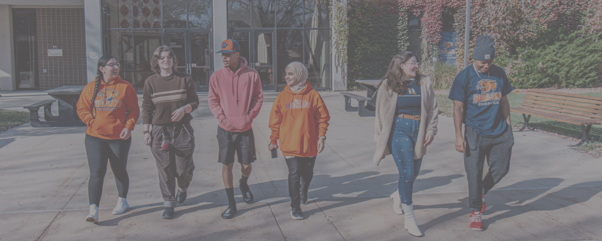 Diverse students of various ethnicities and genders walk on campus.