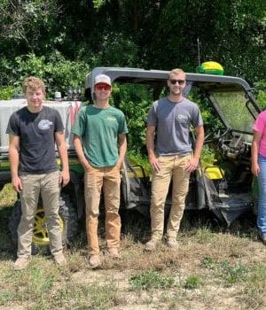 Six agriculture students stand in front of a sprayer machine