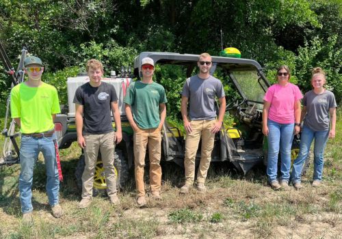 Six agriculture students stand in front of a sprayer machine