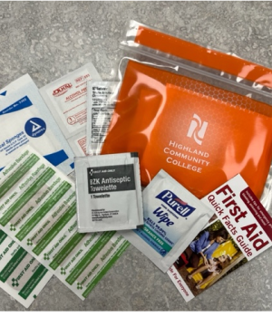 Highland Community College safety kit including bandages, antiseptic wipes, and a small First Aid guide.
