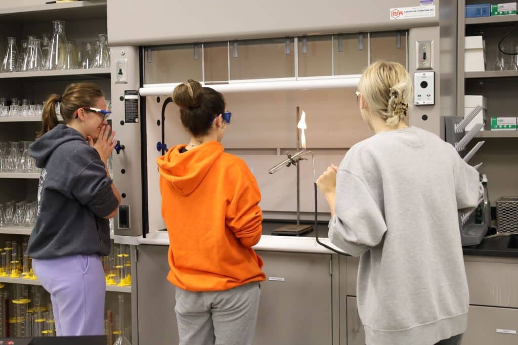 Three students run an experiment in the chemistry lab.