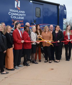 Group of representatives from Highland Community College and the Greater Freeport Partnership prepare to cut the ribbon for HCC's new mobile medical unit.