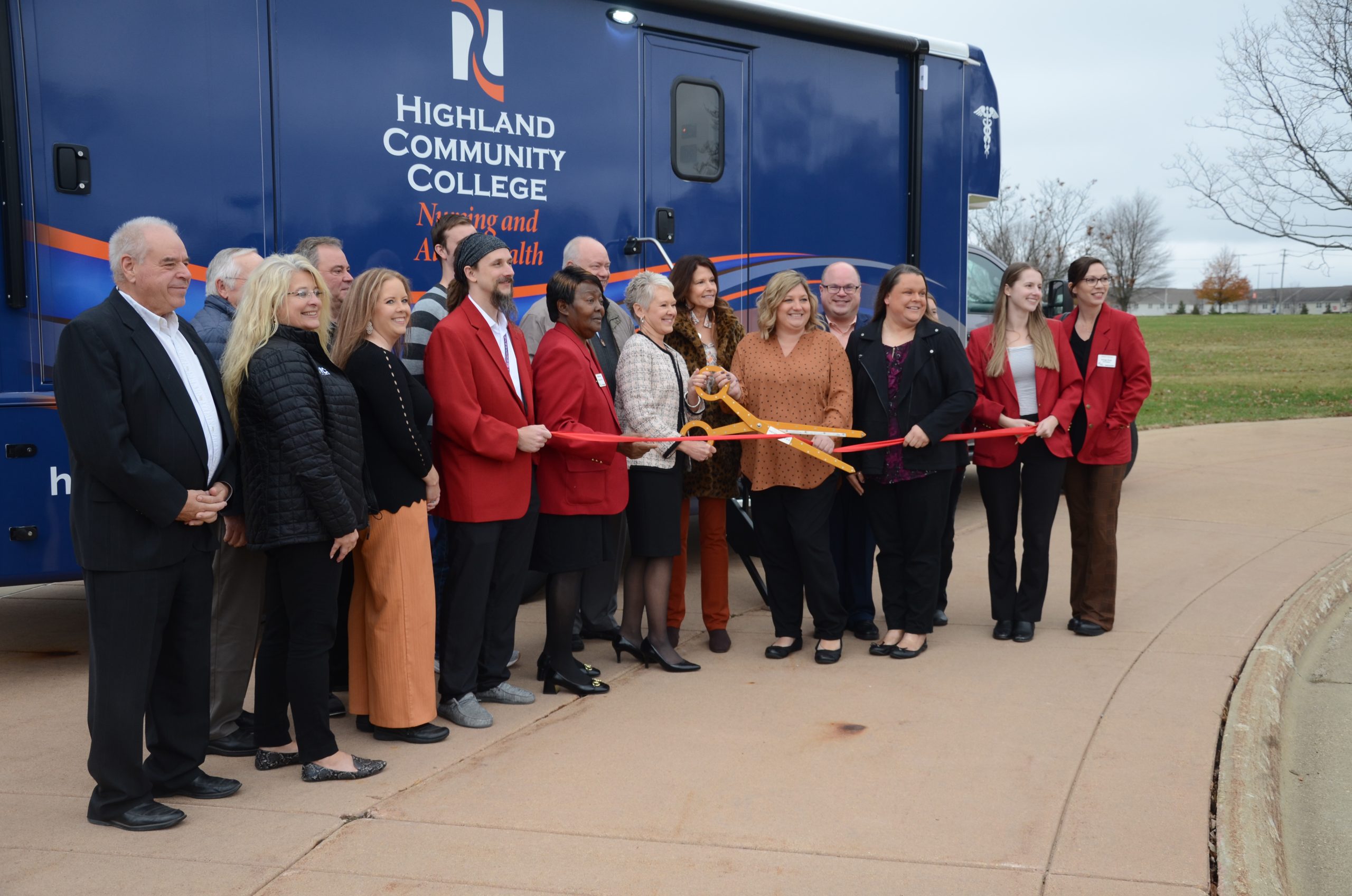 Group of representatives from Highland Community College and the Greater Freeport Partnership prepare to cut the ribbon for HCC's new mobile medical unit.