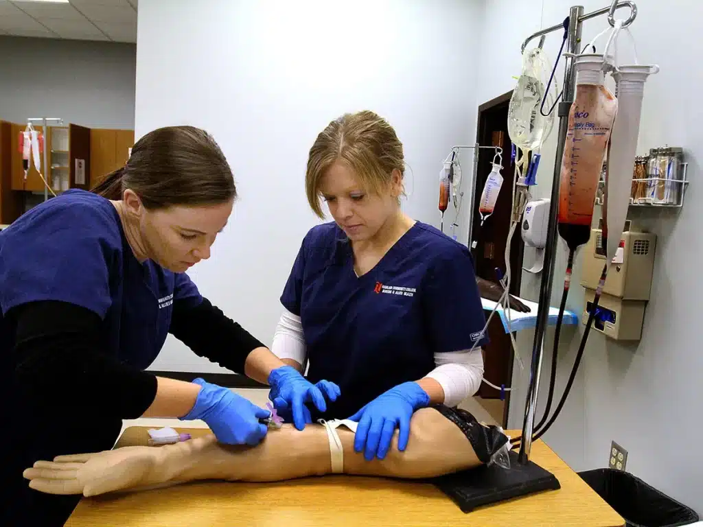 two students practicing medicine on a dummy patient