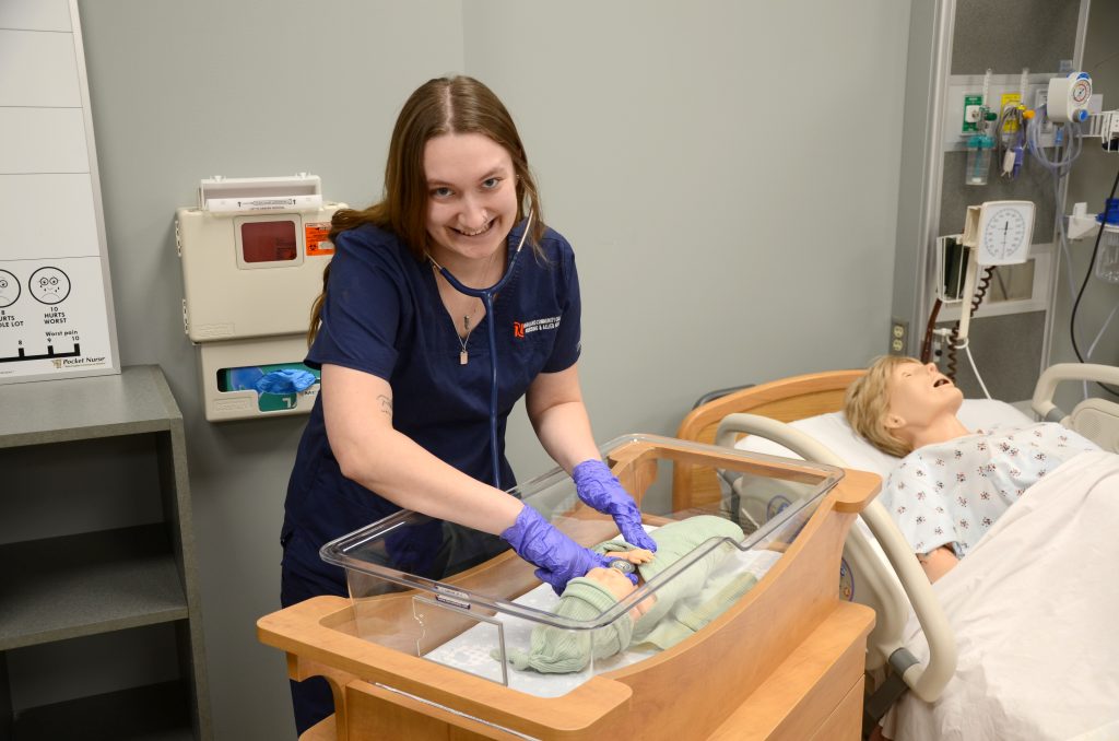 a student practicing  medicine on a dummy baby