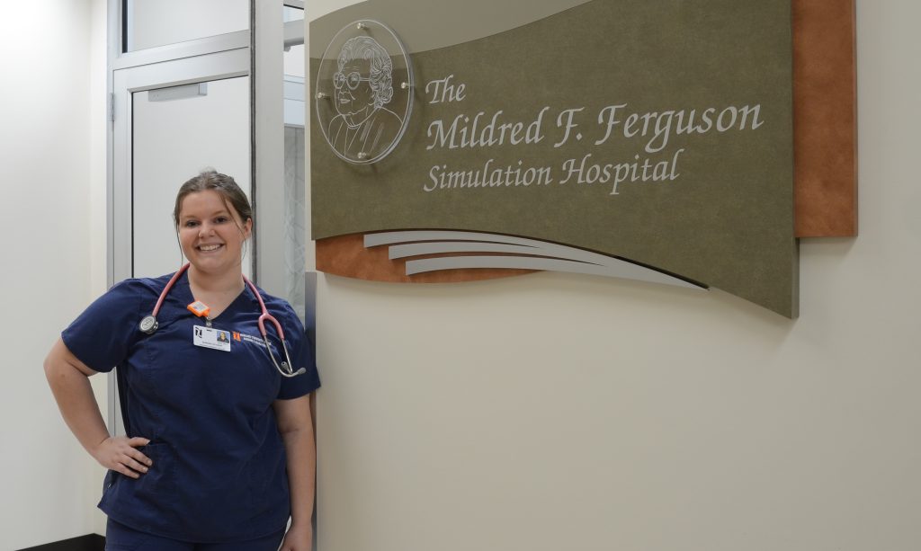 Student portrait next to The Mildred F. Ferguson Simulation Hospital