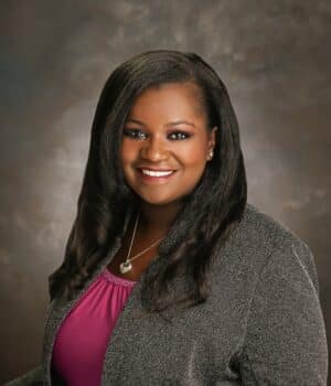Photo of woman in pink shirt and gray blazer.