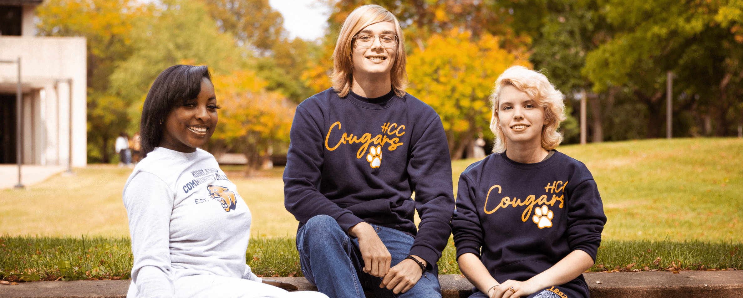 Three students sitting together outside on a nice summer day.