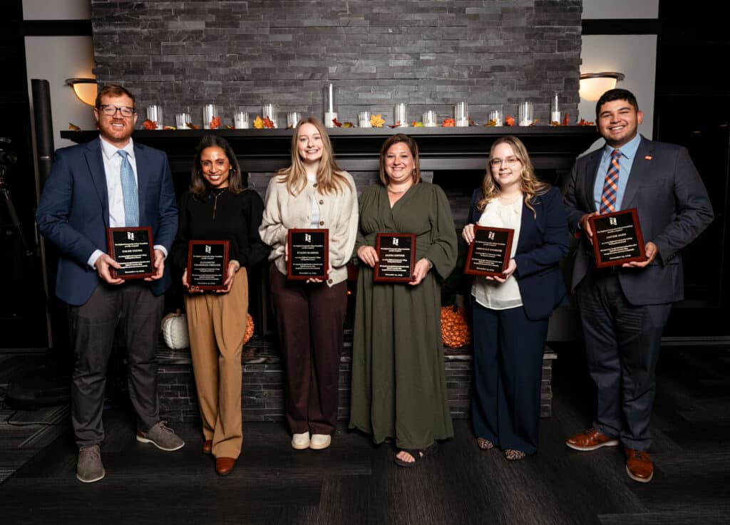 The 2025 Highland Distinguished Alumni in front of a fireplace at the Freeport Club.