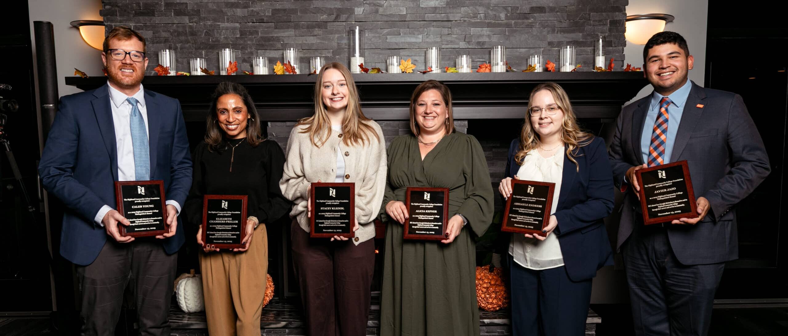 The 2025 Highland Distinguished Alumni in front of a fireplace at the Freeport Club.