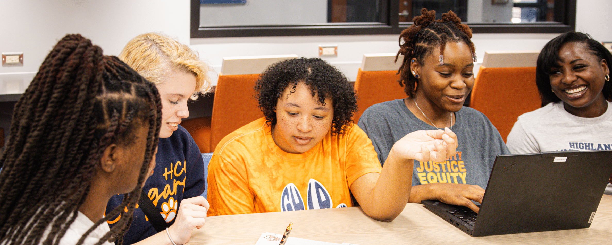 Students reading on a computer. Laughing and registering for class.