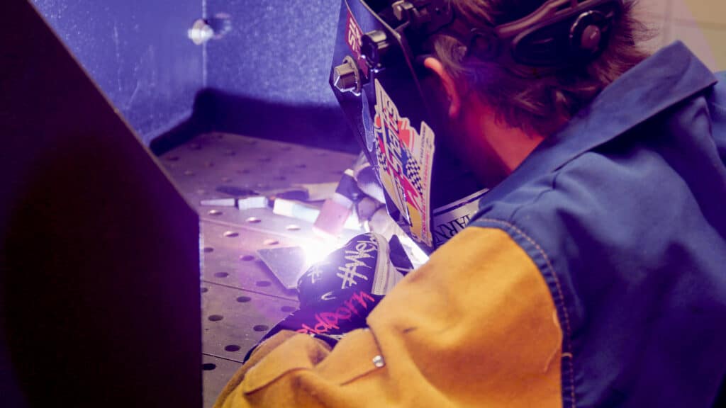 student welding metal at a table