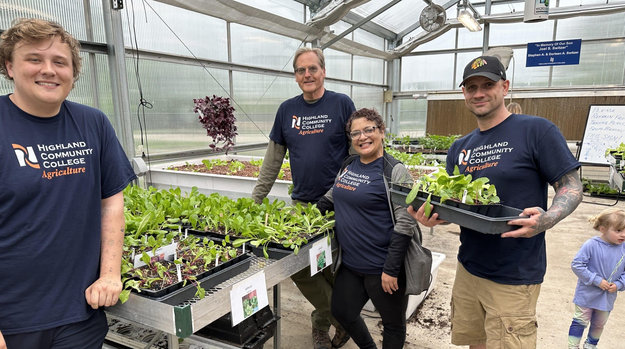 Horticulture students holding plants in a greenhouse
