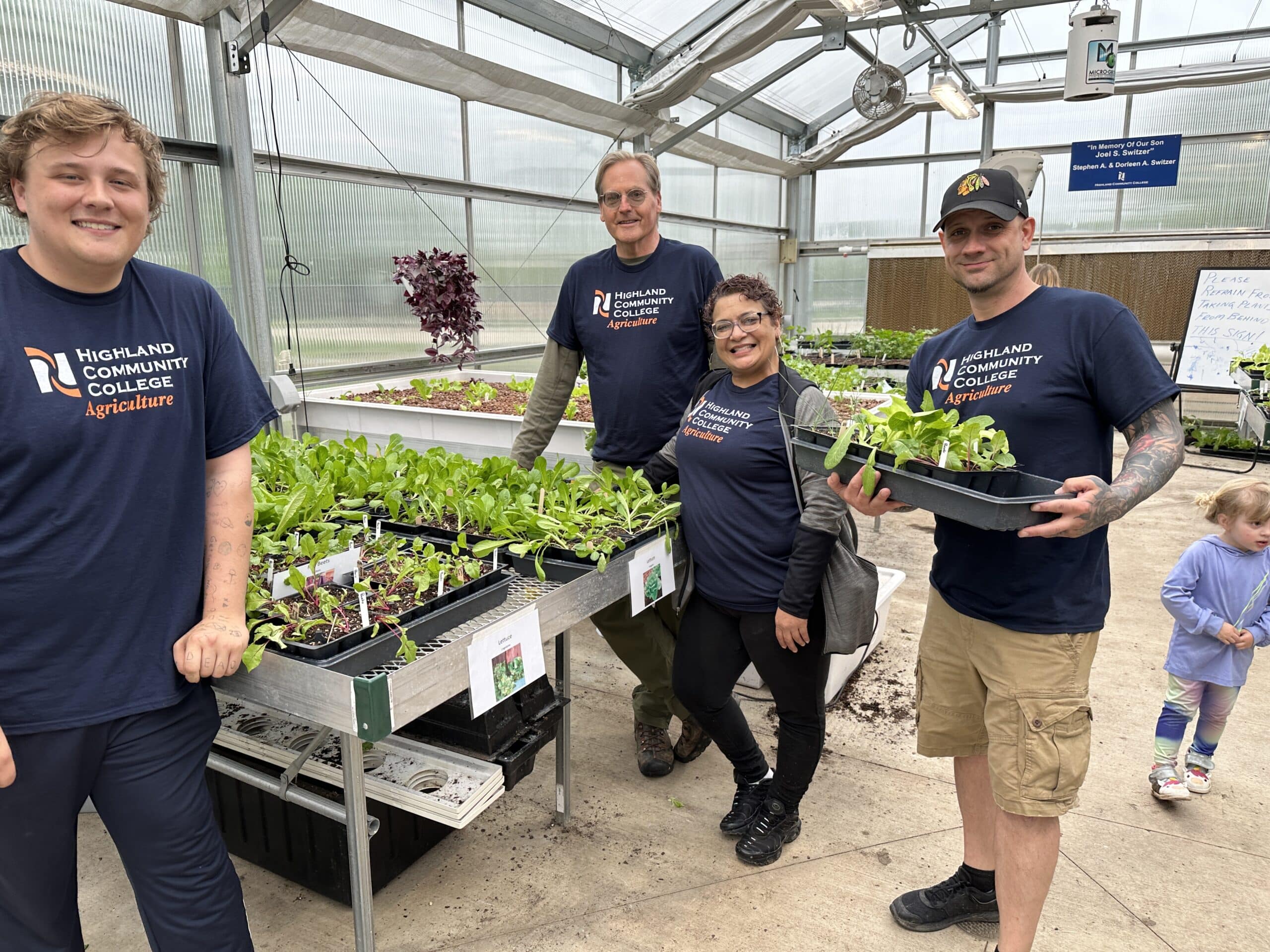 Horticulture students holding plants in a greenhouse