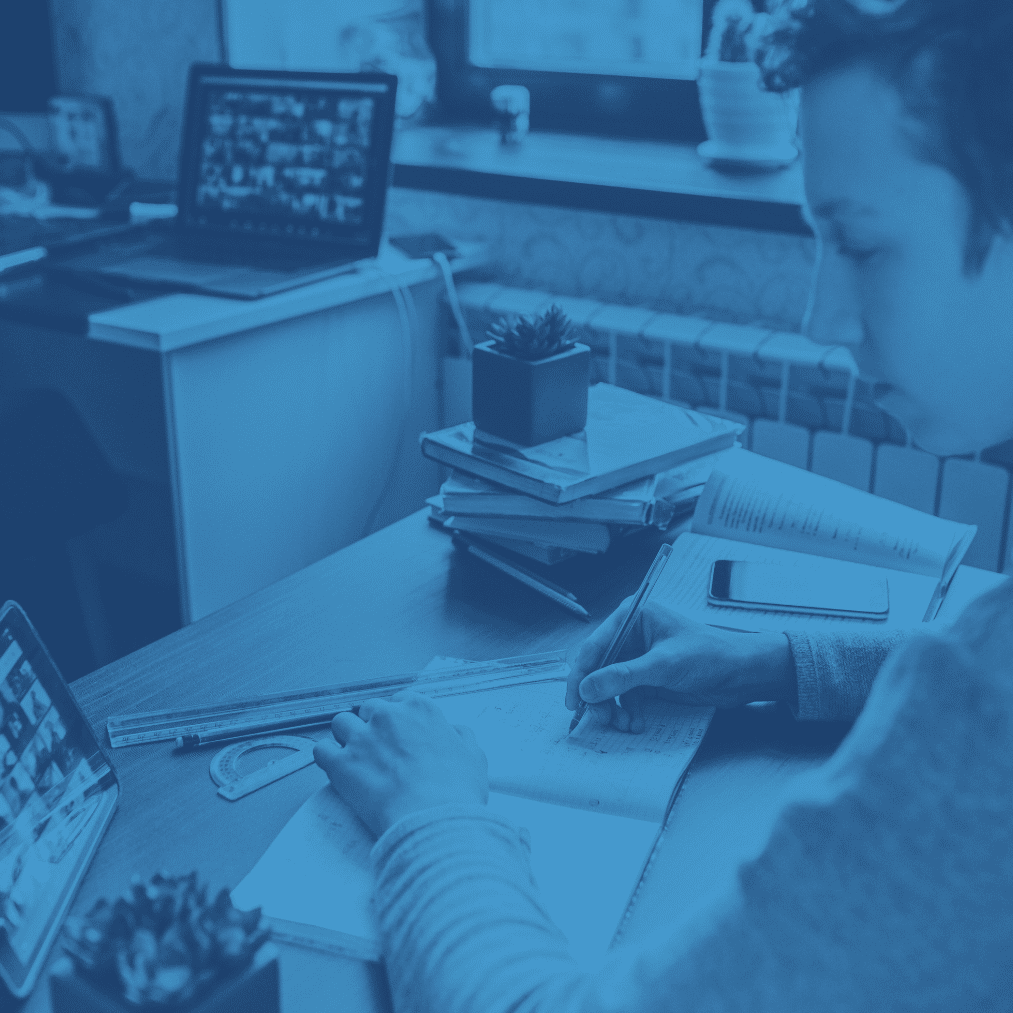 student at a desk infront of computer taking notes