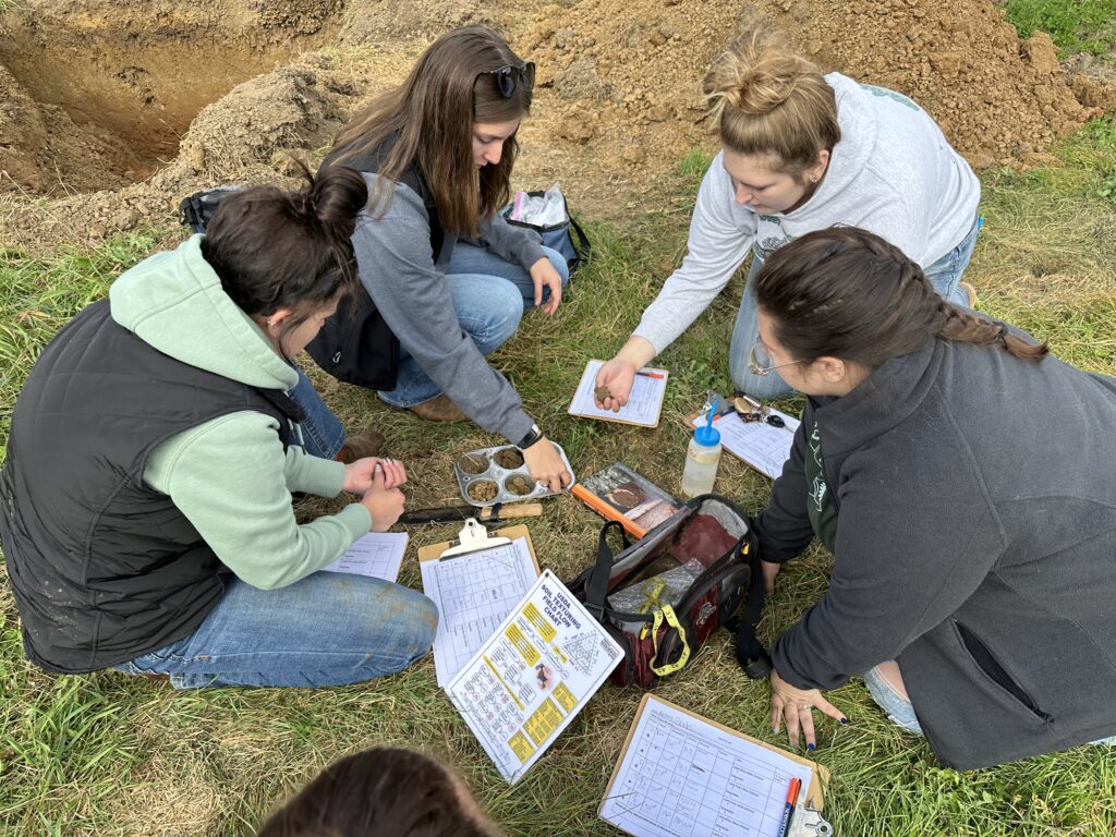 Students sitting in a circle looking at soil