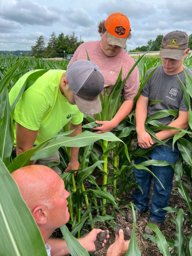 Students working in a field with a teacher looking at soil.