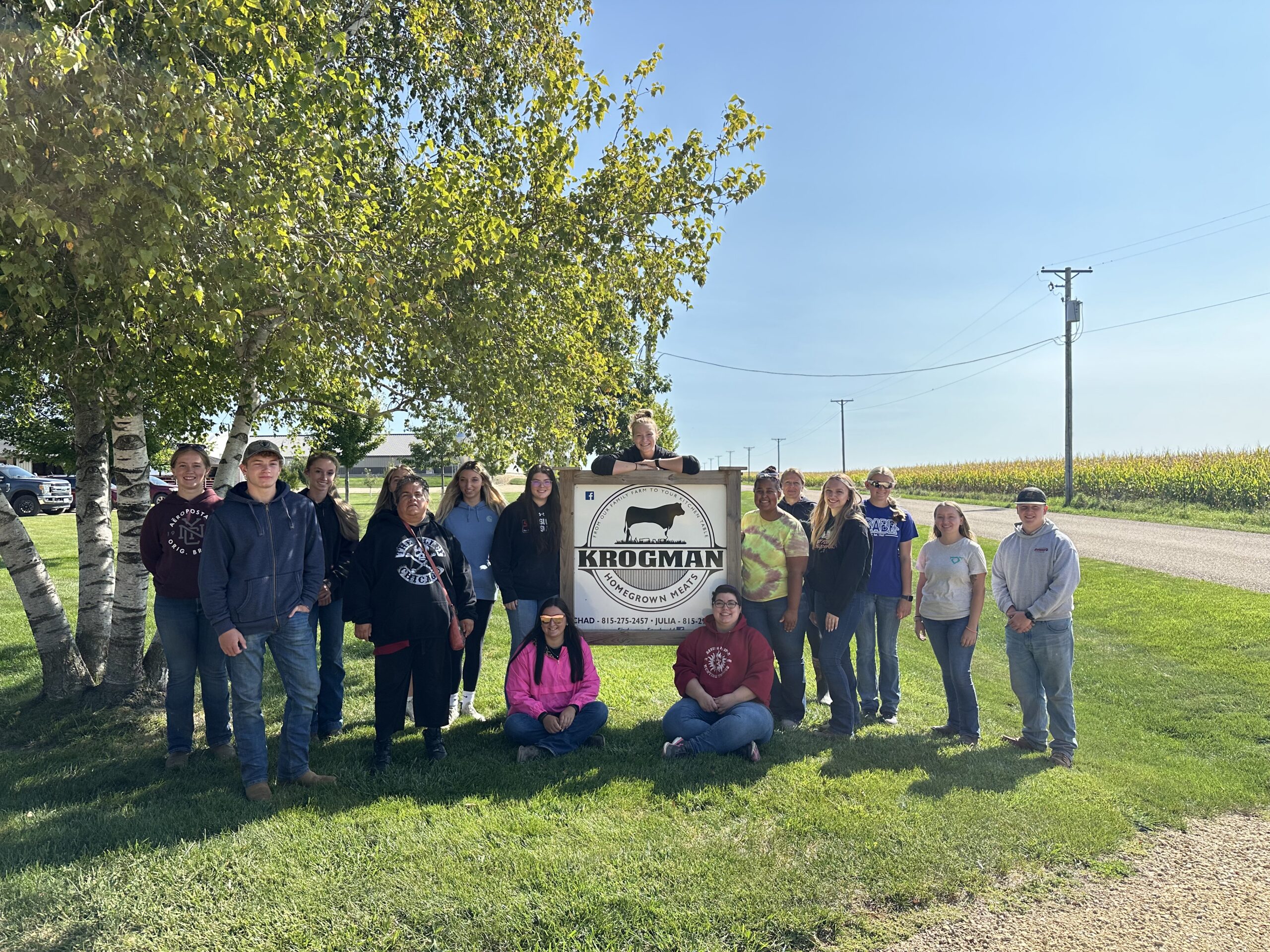 animal science students standing in front of a sign at a farm