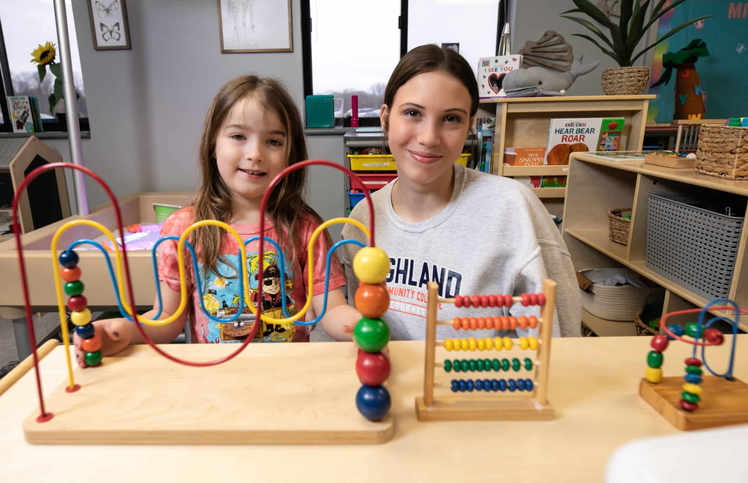 Student and child in early education program class with toy