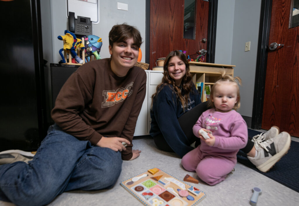 Two students and small child playing on the floor