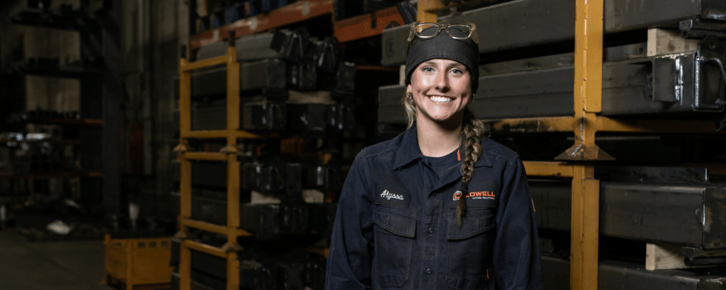 Welding Girl in a factory smiling at the camera with work gear on.