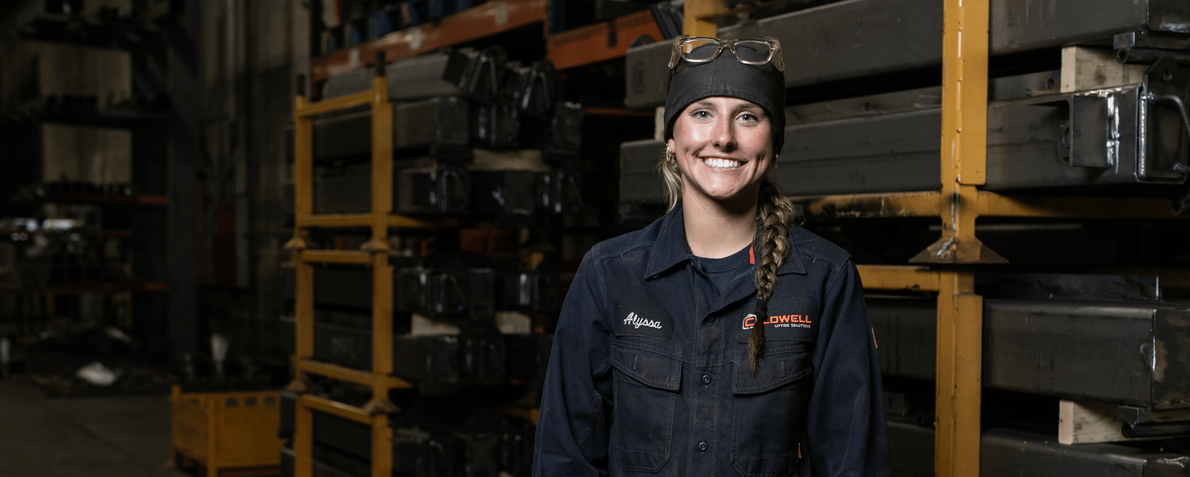 Welding Girl in a factory smiling at the camera with work gear on.
